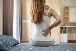 Woman suffering from back ache due to degenerative disc disease on the bed