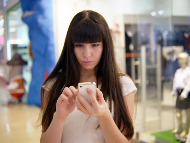 Young woman playing Pokemon GO indoor at shopping center, using smart phone. Girl play the popular smartphone game - catching pokemon in hypermarket mall