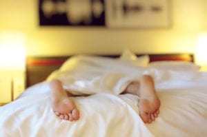 feet hanging off the bed which could cause low back pain from sleeping position on stomach
