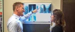 Dr Crist showing a female patient her chiropractic back x-rays