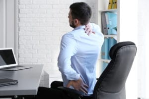 Man hurting from scoliosis pain at computer.