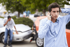 Teenage boy talking on phone after his car wreck
