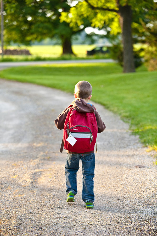 boy walking down street with backpack