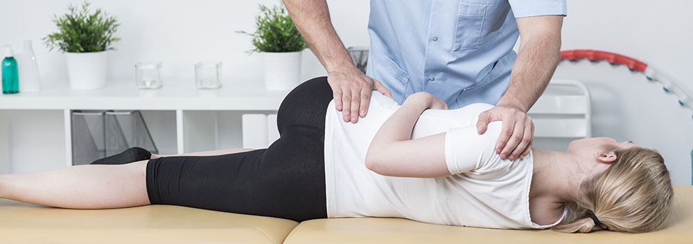 lady on chiropractic table performing exercise with chiropractor's help