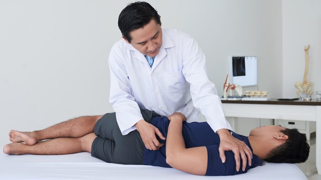 Chiropractor helping a client with lower back pain through stretching and alignment. 